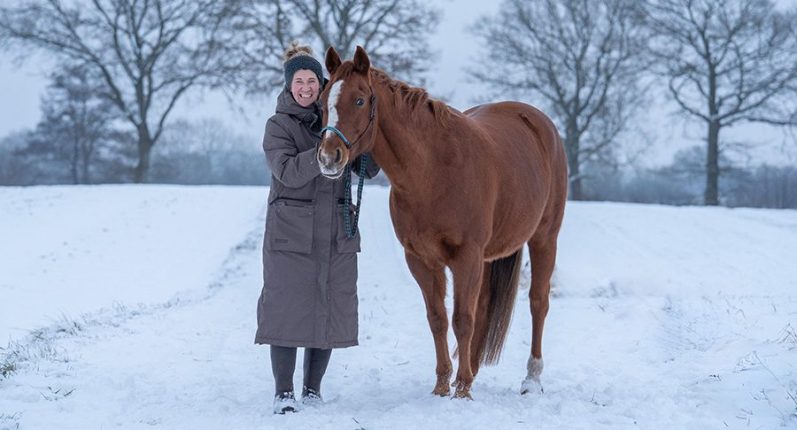 Ein lächelnder Australian Shepherd neben einem kleinen Dackel in einer grünen Wiese.