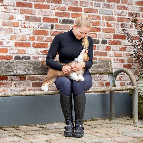 Eine Frau sitzt auf einer Bank und hält einen kleinen Hund auf ihrem Schoß.